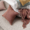 Earth tone fringed linen cushion styled with throw and cushions