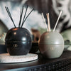 olive green and black ceramic orb diffusers on side table