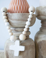 concrete cross and wooden beads draped over candleholder