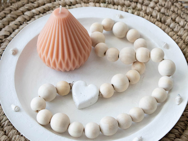 white round shallow dish shell edging styled with candle and wooden beads