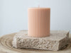 Light peach lined pillar candle on travertine slab