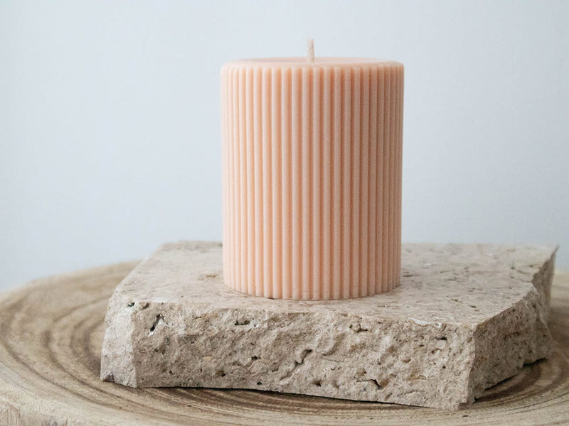Light peach lined pillar candle on travertine slab