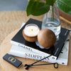 scented candle in glass jar in teak orb on coffee table